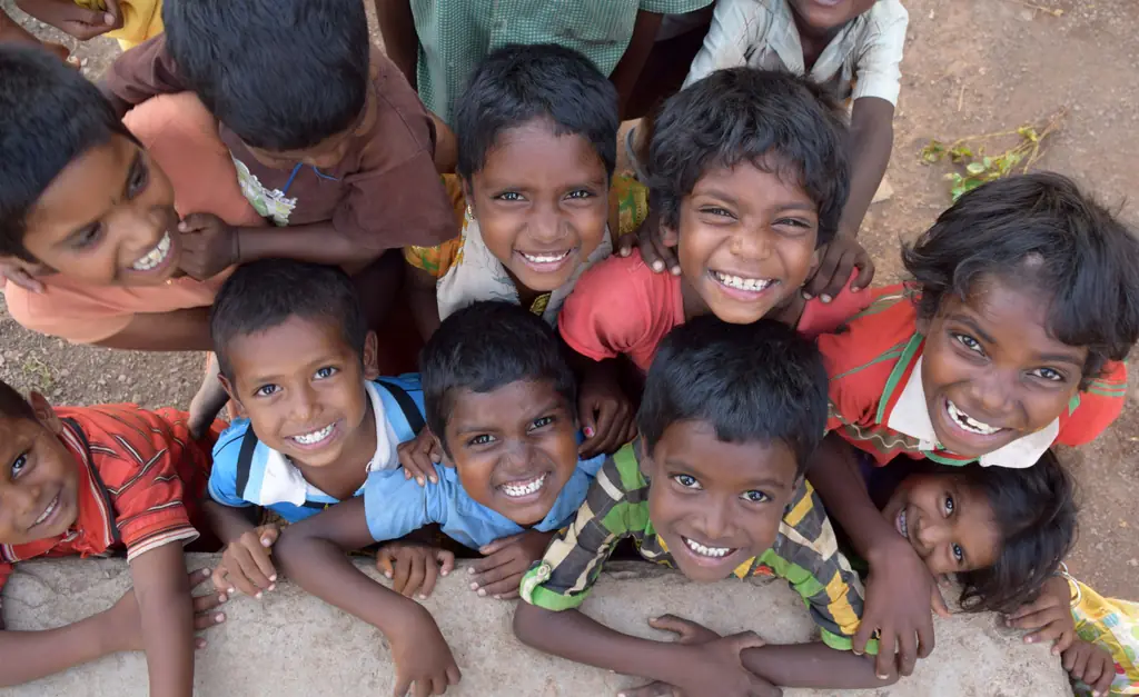 Children crowding together and grinning up at the camera
